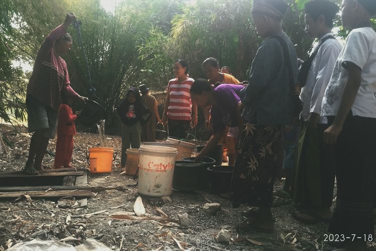Warga Desa Geyer, Kecamatan Geyer, Kabupaten Grobogan, Jawa Tengah mengantre mengangsu air dari belik di sungai yang mengering, Selasa (18/7/2023) sore.
