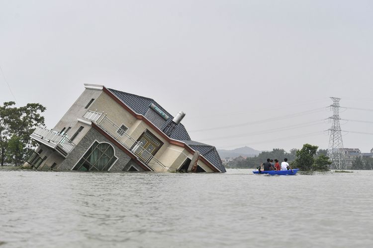 Foto tertanggal 15 Juli 2020 memperlihatkan penduduk mengendarai perahu saat melewati rumah yang hanyut diterjang banjir, di dekat Danau Poyang. Banjir melanda akibat hujan deras yang mengguyur Poyang, Kota Shangrao, Provinsi Jiangxi, China.