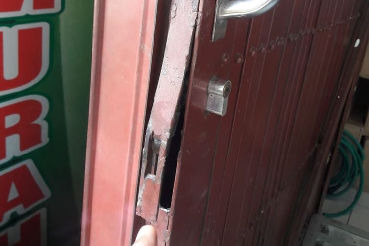 Pintu toko Sahabat Murah di Ngawi yang rusak di congkel pencuri.  2 pencuri yang terekam cctv berhasil menngondol ratusan celana jeans dan uang tunai Rp 3.600.000