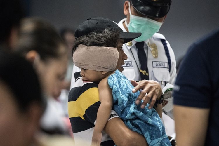 Seorang anak yang menjadi korban kembang api digendong orangtuanya setelah mendapat penanganan di Pusat Medis Jose Reyes Memorial, Manila, 1 Januari 2018.