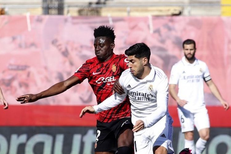 Gelandang Real Madrid, Marco Asensio (kanan), berebut bola dengan pemain Mallorca, Iddrisu Mohamed Baba, pada laga pekan ke-20 Liga Spanyol 2022-2023 yang digelar di Stadion Son Moix, Minggu (5/2/2023). Dalam laga tersebut, Marco Asensio gagal mencetak gol dari tendangan penalti. Real Madrid pun kalah 0-1 dan semakin tertinggal dari Barcelona selaku pemimpin klasemen Liga Spanyol 2022-2023.