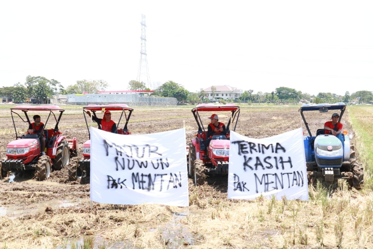 Beberapa petani sedang mengibarkan spanduk bertuliskan tanda terima kasih kepada Menteri Pertanian.