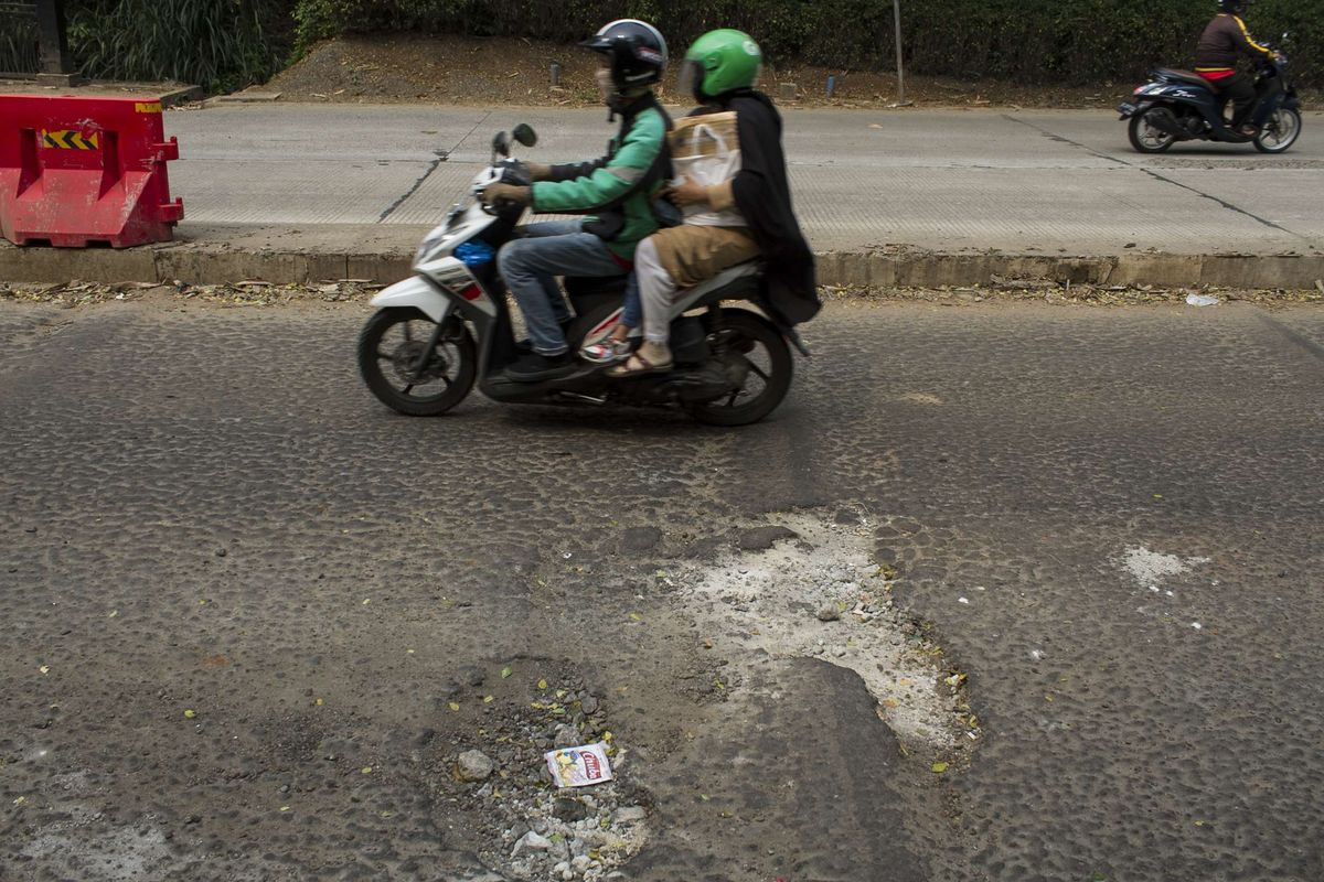 Pengendara melintasi jalan yang berlubang di Grand Depok City (GDC) Grand Depok City, Depok, Jawa Barat, Rabu, (11/12/2019). Beberapa jalan sepanjang GDC masih berlubang dan bergelombang.