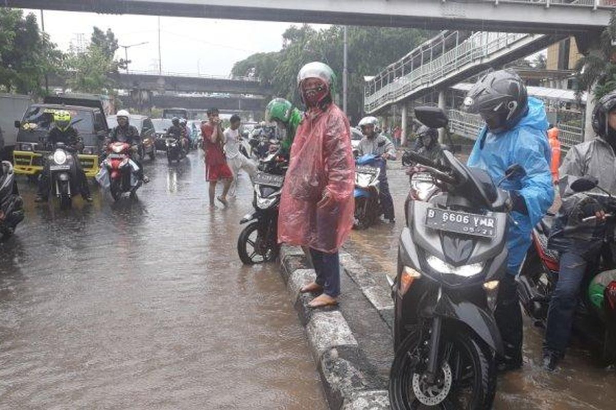 Pengendara sepeda motor saat mengangkat kendaraannya dari sisi kiri melewati separator Jalan DI Panjaitan, Jatinegara, Jakarta Timur, Jumat (24/1/2020).  