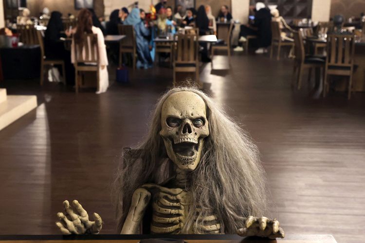 Sesosok zombie duduk di meja bertema horor di restoran Shadows di Riyadh, Arab Saudi, 19 Januari 2022. Restoran ini menawarkan pelanggan pengalaman unik dengan menyajikan hidangan di samping tengkorak dan darah ditemani zombie serta vampir.