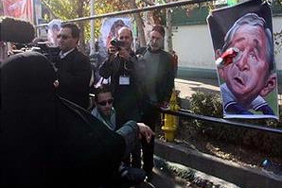 Wanita Iran melemparkan sepatunya ke poster Presiden AS George W Bush di Teheran, Jumat (26/12).