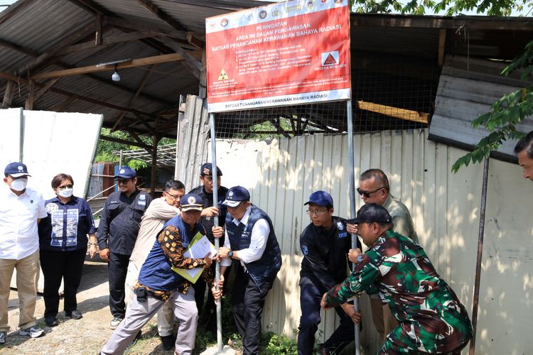 Petugas melepaskan plang penyegelan di pabrik Cikande yang sebelumnya terpapar radioaktif. 