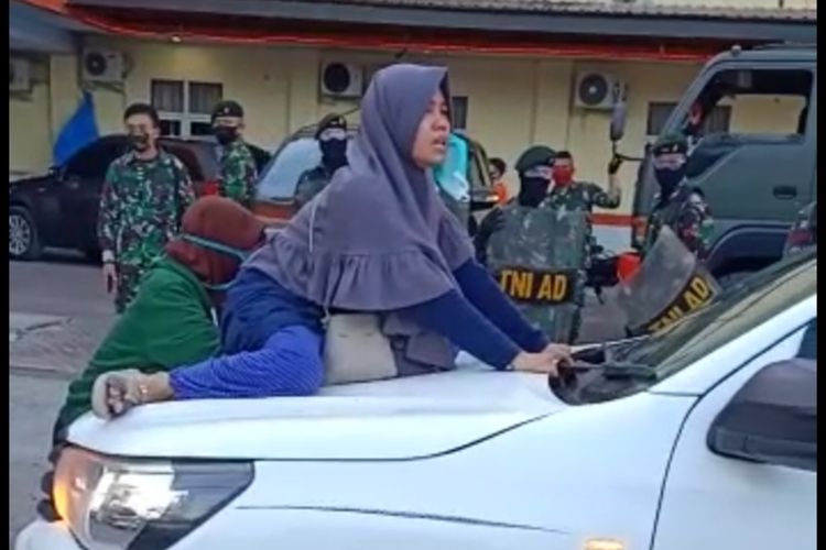 Salah satu anak dari pasien PDP Covid-19 di Rumah Sakit Bhayangkara Makassar saat menghalangi mobil petugas yang membawa ibunya di pemakaman khusus Covid-19, Senin (15/5/2020) lalu.