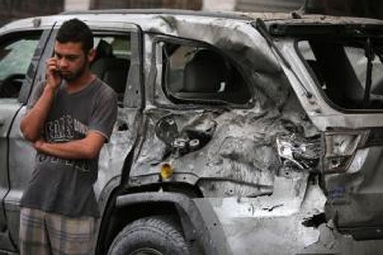Seorang pria bersandar di bangkai mobil yang meledak di distrik Kerrada, Baghdad sambil menelepon. Serangkaian serangan bom sepanjang Rabu (20/11/2013) di sejumlah permukiman Syiah di Baghdad menewaskan sedikitnya 29 orang.