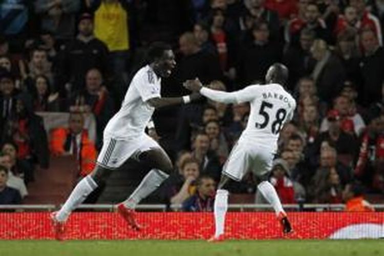 Striker Swansea City, Bafetimbi Gomis (kiri), merayakan gol yang dicetak ke gawang Arsenal pada laga Premier League di Stadion Emirates, London, Senin (11/5/2015).