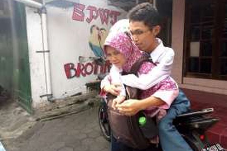 Tatik Sukilah saat mengendong putranya Erry Susilo turun dari ojek menuju rumah kontraknya 