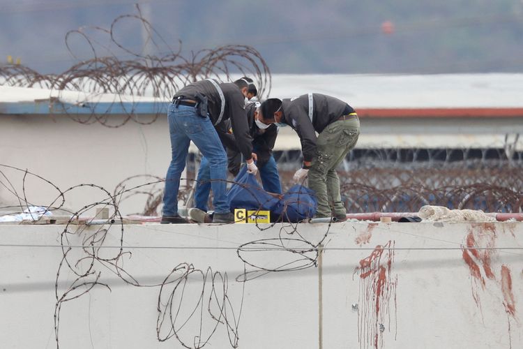 Anggota kepolisian Ekuador memindahkan mayat seorang narapidana yang tewas di atap pavilion Penjara Guavas 1 di Guayaquil, Ekuador, pada 13 November 2021. Pertikaian di penjara itu menyebabkan 68 narapidana tewas.