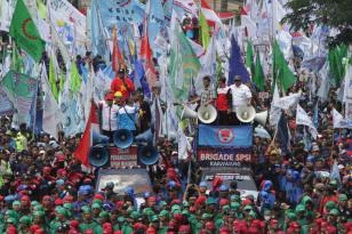 Massa buruh yang tergabung dalam Gerakan Buruh Indonesia berdemonstrasi melintasi Jalan Medan Merdeka Barat, Jakarta Pusat, Selasa (1/9/2015). Demonstrasi dilakukan karena adanya ancaman PHK besar-besaran seiring dengan anjloknya nilai tukar rupiah terhadap dolar AS.