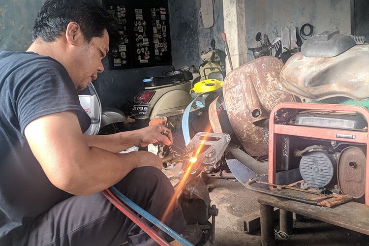 Pemilik bengkel restorasi vespa di Solo, Mulyono atau Lik Mul tengah melakukan pengelasan di bengkelnya.