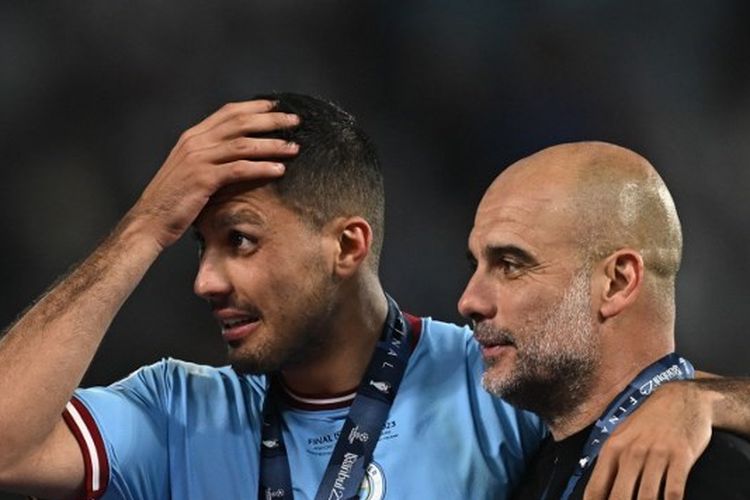 Gelandang Manchester City, Rodri, berselebrasi bersama pelatih Man City, Pep Guardiola, dalam seremoni pemberian medali seusai final Liga Champions 2022-2023 yang mempertemukan Inter Milan vs Man City di Stadion Olimpiade Ataturk pada 10 Juni 2023. Terkini, Rodri mengaku tak pernah mendapatkan istirahat cukup selama kampanye musim lalu bersama Man City. (Foto oleh Paul ELLIS / AFP)