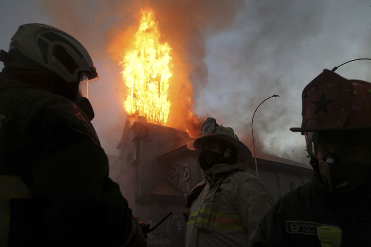 Tim pemadam kebakaran berusha menjinakkan api di Gereja Parroquia de La Asuncion yang dibakar dalam unjuk rasa di Santiago, Chile, pada 18 Oktober 2020.