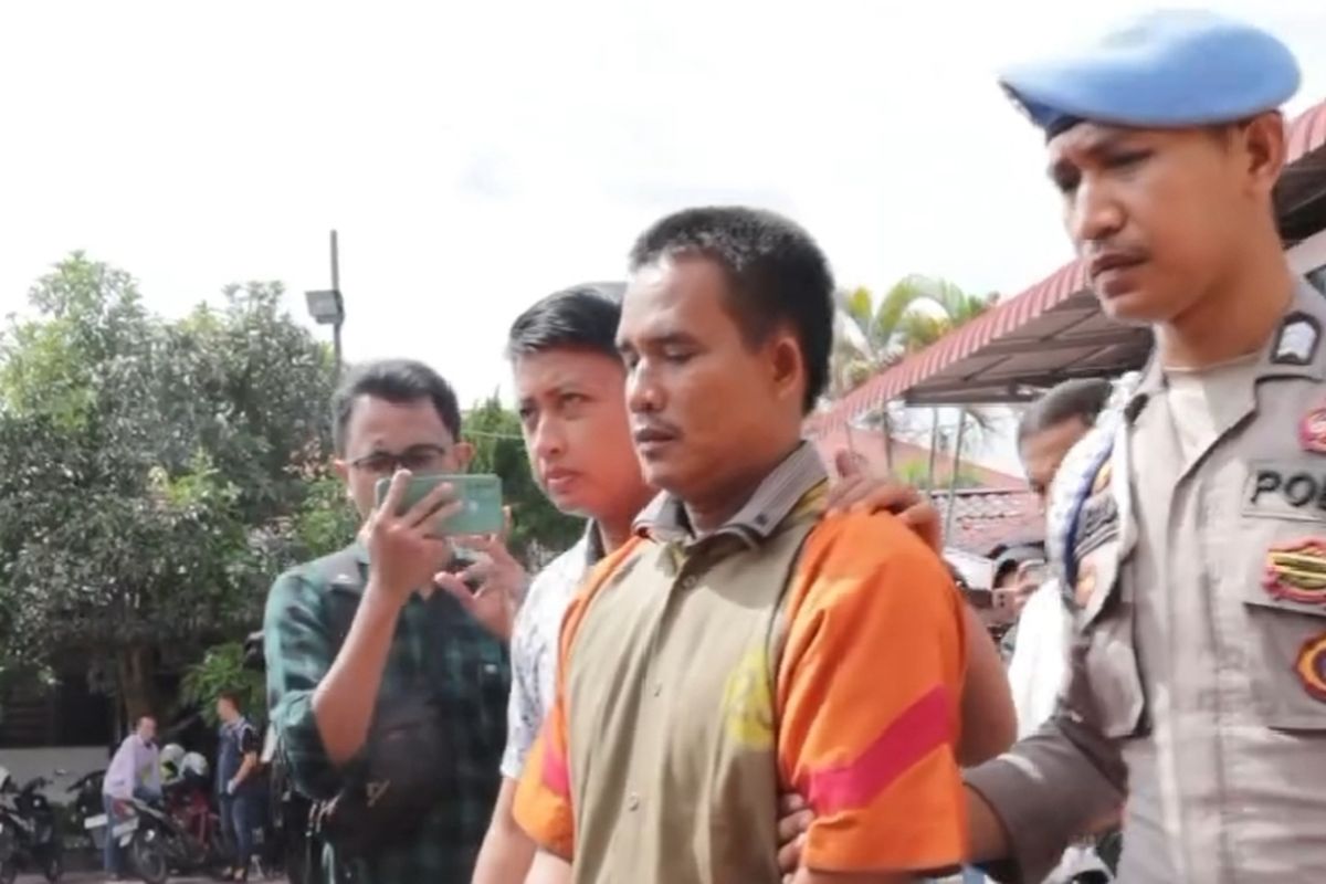 Polisi saat menggiring pelatih renang bernama Jaimes Simare- mare di Polres Asahan, Selasa (6/8/2024). Dia ditangkap karena menendang guru renang wanita hingga pingsan karena rebutan area latihan renang.