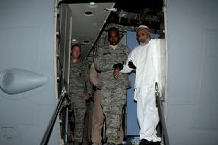 Seorang prajurit AS membantu Ibrahim Othman Idris turun dari pesawat di bandara internasional Khartoum setelah tiba dari Guantanamo, Kuba. Dua tahanan asal Sudah dipulangkan sebagai bagian percepatan penutupan tahanan militer AS di Guantanamo.