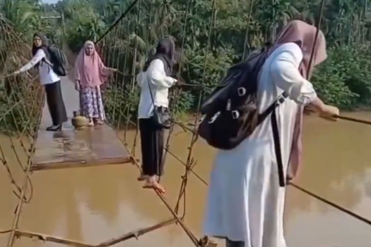 Empat guru bertaruh nyawa bergelantungan melewati sebuah jembatan di Desa Simpang Limbur Merangin, Jambi. Desa ini jauh berada di pedalaman Jambi..
