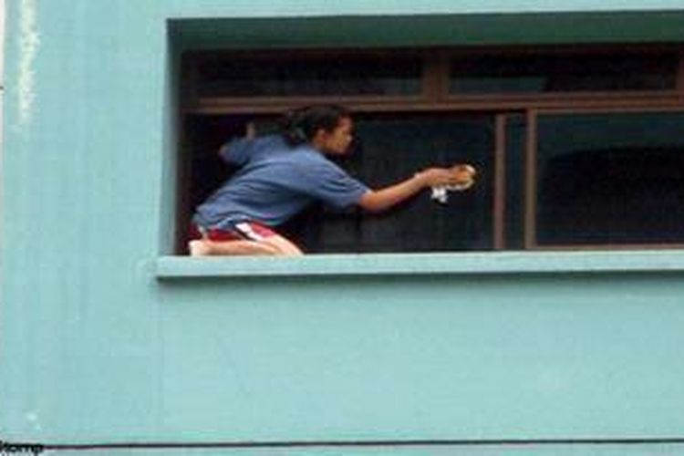 Seorang pekerja rumah tangga membersihkan jendela tanpa alat perlindungan apapaun di sebuah gedung apartemen di Singapura.