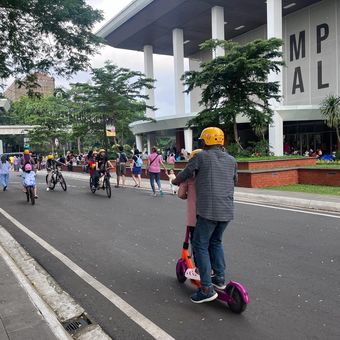 Pengunjung Taman Mini Indonesia Indah (TMII) nampak berkeliling menggunakan skuter dan sepeda pada Kamis (11/4/2024). 