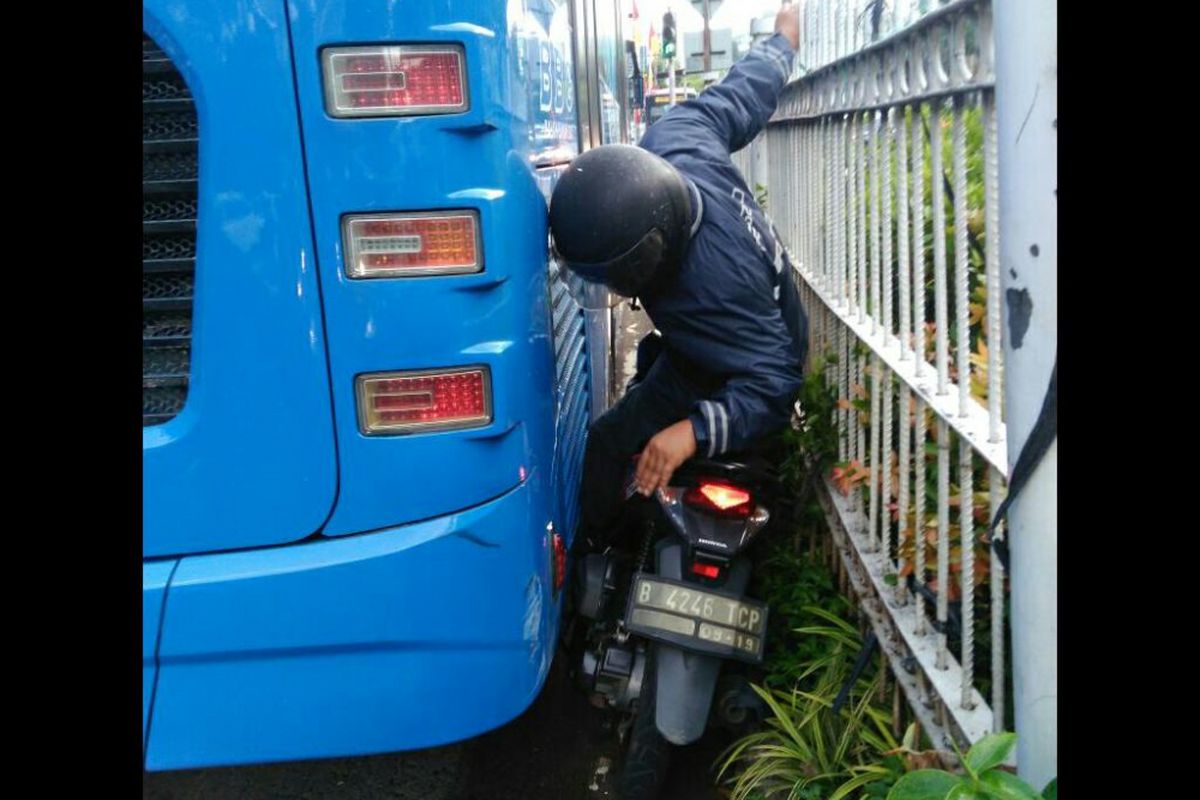 Nekat menerobos jalur transjakarta, pengendara sepeda motor ini terjepit badan bus.