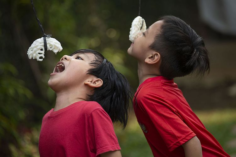 Sejumlah bocah mengikuti lomba makan kerupuk untuk memeriahkan hari ulang tahun (HUT) Ke-76 Kemerdekaan Republik Indonesia (RI) di salah satu rumah di Cimanggu, Bogor, Jawa Barat, Selasa (17/8/2021). Meski masih di tengah pandemi, lomba-lomba dalam rangka memeriahkan HUT RI tetap dilakukan secara internal di lingkungan keluarga untuk mencegah penularan Covid-19.