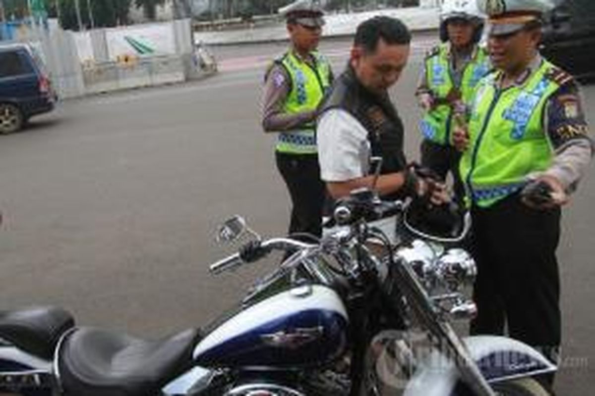 Seorang pengendara Harley Davidson B 6168 ESG dihentikan aparat kepolisian untuk ditilang karena melintasi Jalan MH Thamrin, yang merupakan kawasan terlarang sepeda motor, Minggu (18/1/2015). Seperti diketahui, sepeda motor dilarang melintasi yakni Jalan MH Thamrin hingga Jalan Medan Merdeka Barat, Jakarta Pusat. Per 18 Januari 2015, polisi menerapkan sanksi tilang bagi pelanggarnya.