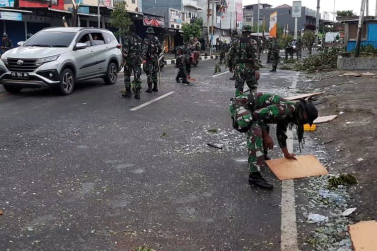 Aparat TNI AD sedang membersihkan pecahan kaca yang masih berserakkan di ruas Jalan Yos Sudraso, pasca-kerusuhan di Manokwari, Selasa (20/8/2019).