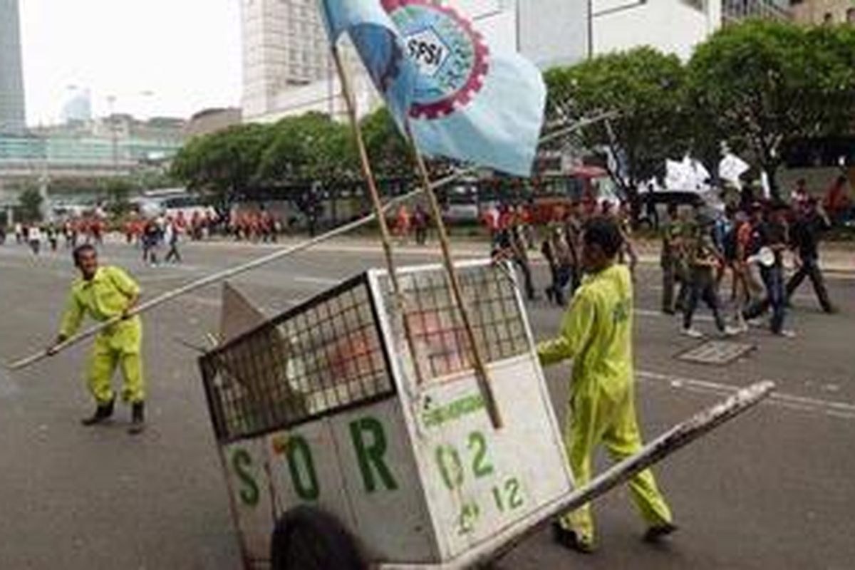 Buruh kebersihan, yang merupakan tenaga outsourcing, menyapu sampah yang ditinggalkan oleh buruh saat berdemonstrasi di Jalan MH Thamrin, Jakarta, beberapa waktu lalu.