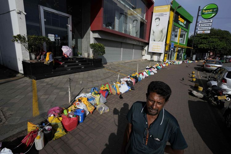 Dampak krisis Sri Lanka bangkrut, seorang pria berdiri mengantre di luar SPBU untuk membeli minyak tanah di samping jejeran jeriken kosong akibat kelangkaan minyak goreng di Colombo, ibu kota Sri Lanka, Kamis (23/6/2022).