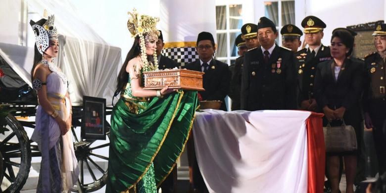 Bupati Purwakarta Dedi Mulyadi menerima bendera Merah Putih dari sosok Nyi Ratu Kidul sebelum diserahkan pada Paskibra yang sudah dikukuhkan. 