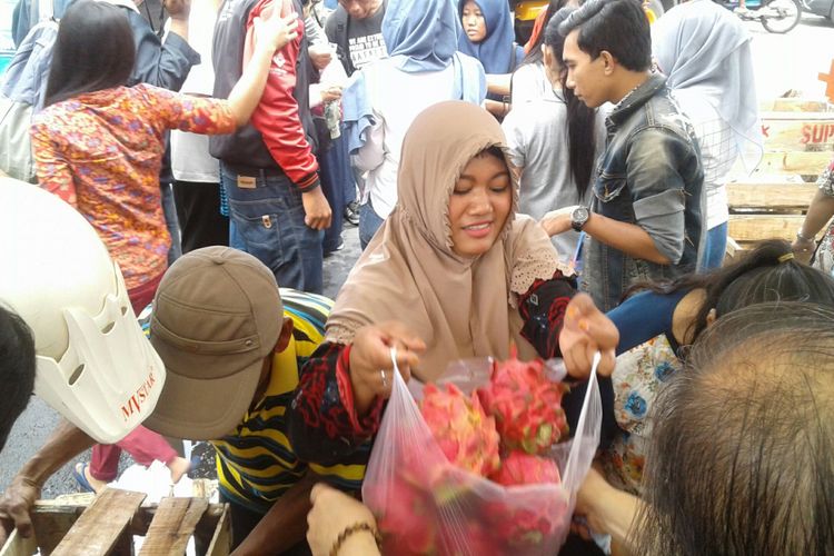Warga berebut buah naga dengan harga murah di depan Pasar Gede Solo, Jawa Tengah, Jumat (12/1/2018). 