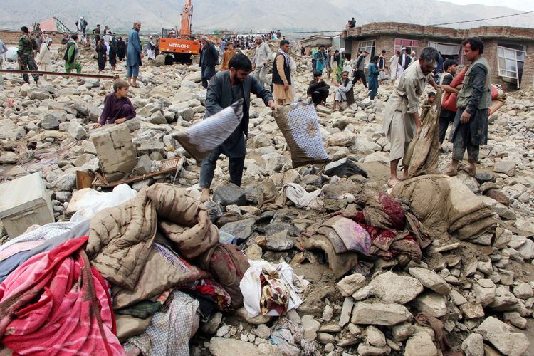 Warga Afghanistan mencari barang-barang mereka setelah dilanda banjir bandang yang tewaskan ratusan orang di Charikar, ibu kota Provinsi Parwan, Rabu (26/8/2020).