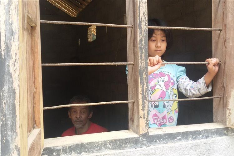 Putri Depi Nur’aini, 9 tahun, dan Sakijo, 58, di dalam rumahnya di Dusun Tangkisan 3, Desa Hargomulyo, Kulon Progo, DIY. Sakijo dulunya penyadap nira kelapa. Ia lumpuh setelah kali kedua jatuh dari pohon kelapa. Kini, Sakijo hanya berteman anak semata wayangnya, Depi, di rumah mereka yang mungil. Perhatian dan bantuan juga datang dari kerabat dekat yang berada di kanan kiri rumahnya. 