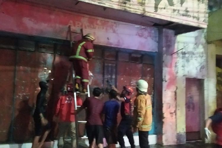 Petugas Damkar Kota Pekalongan jawa Tengah mencoba menjebol pintu ruko yang terbakar.