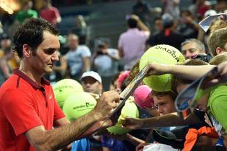 Petenis Swiss, Roger Federer, memberikan tanda tangan setelah meraih kemenangan atas petenis Australia, John Millman, pada babak kedua Brisbane International, Kamis (8/1/2015). Federer menang 4-6, 6-4, 6-3.