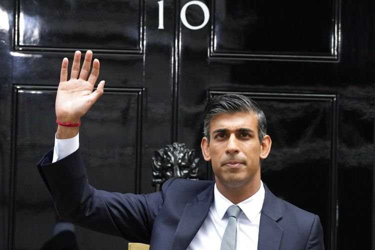 Perdana Menteri Inggris yang baru Rishi Sunak melambai setelah tiba di Downing Street di London, Selasa, 25 Oktober 2022, setelah kembali dari Istana Buckingham di mana ia secara resmi ditunjuk oleh Raja Inggris Charles III.