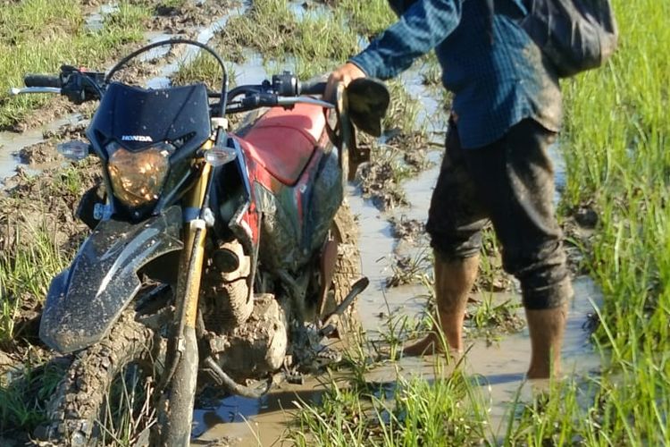 Salah seorang guru SDN Buddi saat melewati jalan poros kabupaten menuju sekolah tersebut
