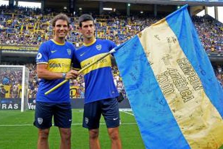 Petenis Spanyol, Rafael Nadal (kiri) dan petenis Serbia, Novak Djokovic, memakai jersey Boca Juniors dan berpose di staion La Bombonera, saat Boca menghadapi All Boys pada laga lanjutan Divisi Satu Argentina, di Buenos AIres, Minggu (24/11/2013).