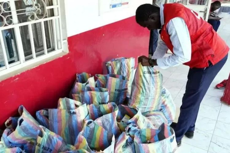 Anggota Palang Merah Gambia memeriksa karung-karung berisi obat batuk yang dikumpulkan.

