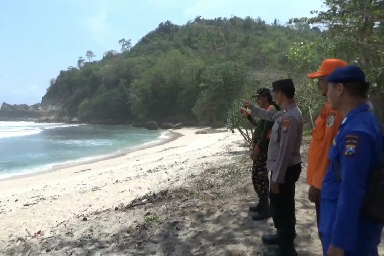 Petugas menunjukkan tebing tempat korban hilang tersapu ombak di Pantai Sanggar Kecamatan Tanggunggunung Kabupaten Tulungagung Jawa Timur, Senin (13/10/2023).