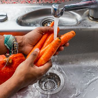 Ilustrasi mencuci sayuran dan buah di dapur.