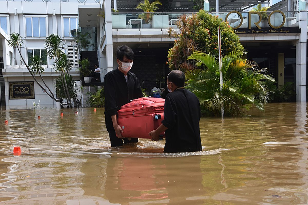 Petugas hotel membawa koper milik tamu saat banjir melanda kawasan Kemang, Jakarta Selatan, Sabtu (20/2/2021). Banjir yang terjadi akibat curah hujan tinggi serta drainase yang buruk membuat kawasan Kemang banjir setinggi 1,5 meter.