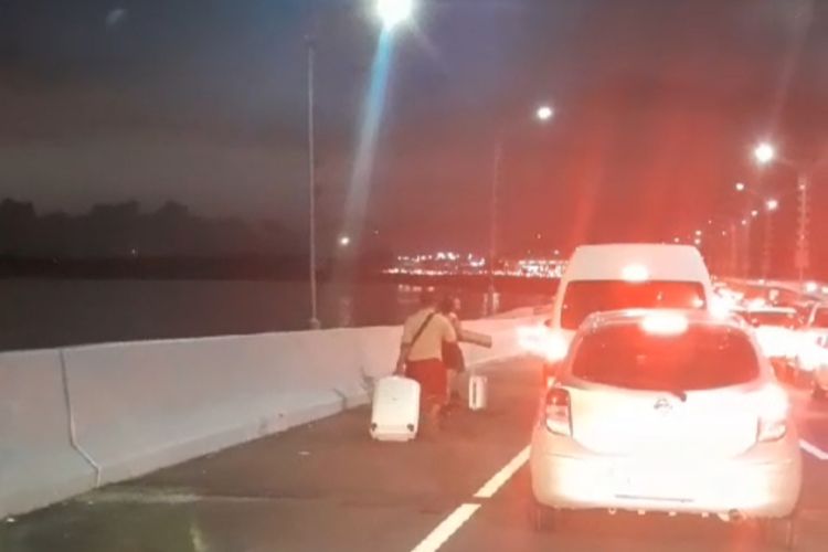 Sejumlah wisatawan tampak turun dari kendaraan imbas kemacetan yang terjadi di Tol Bali Mandara menuju Bandara Ngurah Rai, Badung, Bali, pada Jumat (29/12/2023). /Dok.tangkapan layar video warga