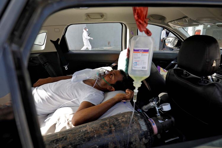 Seorang pasien dengan gangguan pernapasan berbaring di dalam mobil sambil menunggu untuk masuk rumah sakit Covid-19 untuk perawatan, di tengah penyebaran penyakit virus corona (Covid-19), di Ahmedabad, India, Kamis (22/4/2021).