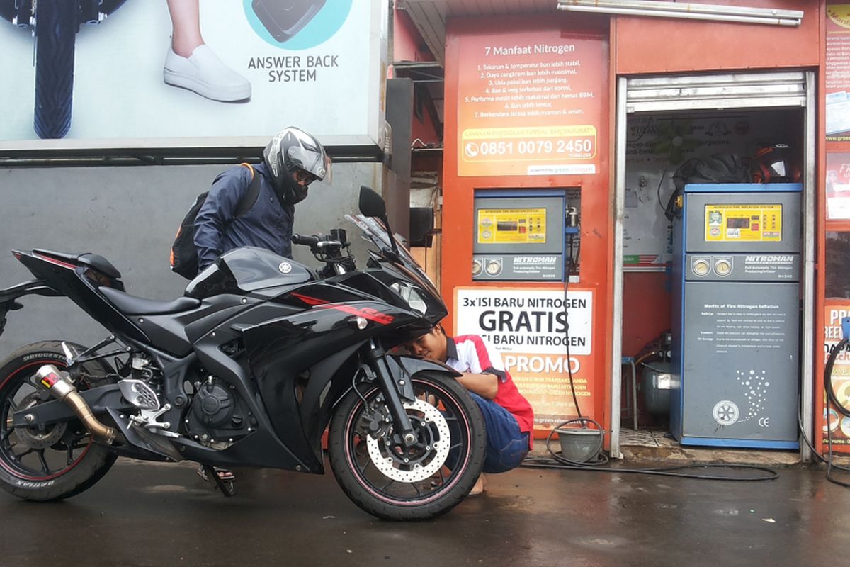 Seorang petugas outlet pengisian ban dengan nitrogen di salah satu SPBU Pertamina di Jalan Margonda, Depok sedang melayani pelanggan pada Kamis (8/2/2018).