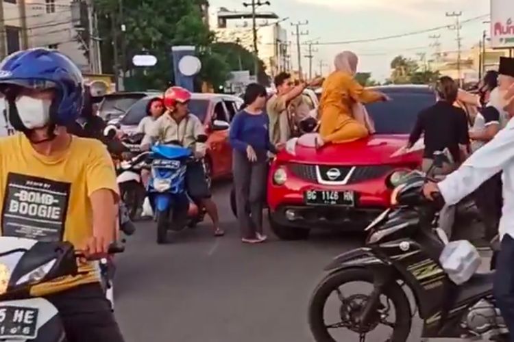 Seorang wanita menggunakan baju kuning nekat naik ke atas kap mobil milik oknum polisi di Polres Lubuk Linggau inisial A lantaran diduga sedang membawa wanita lain di dalam mobil.