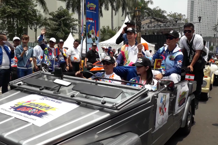Mantan perenang nasional Richard Sam Bera dan Ketua Inapgoc Raja Sapta Oktohari membawa obor Asian Para Games 2018 di atas mobil klasik, Minggu (30/9/2018).