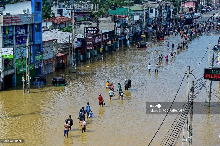 Warga korban banjir Sri Lanka berjalan menerjang genangan air di pinggiran Ibu Kota Colombo, 30 November 2025. Banjir dan tanah longsor kali ini menewaskan sedikitnya 334 orang, terparah sejak 2023. Sri Lanka Tetapkan Keadaan Darurat usai Banjir Tewaskan 330 Korban Lebih